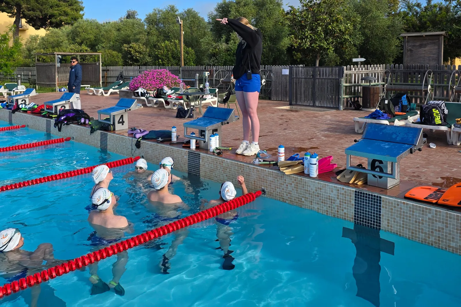 Coach on deck briefing a group of swimmers in their lane