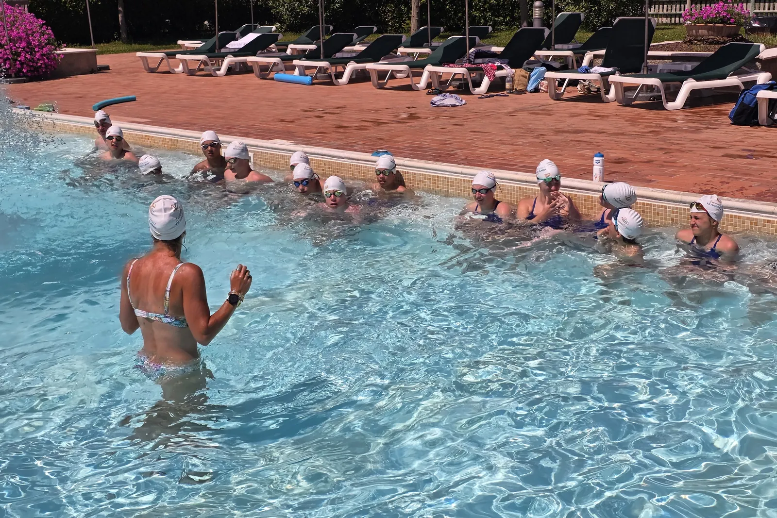 Coach in het water legt een oefening uit aan een groep zwemmers langs de kant